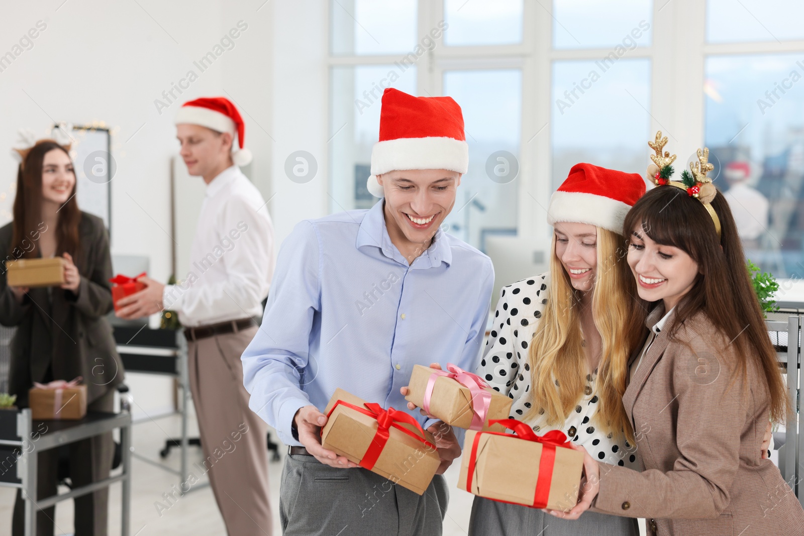 Photo of Happy coworkers with gifts at office Christmas party