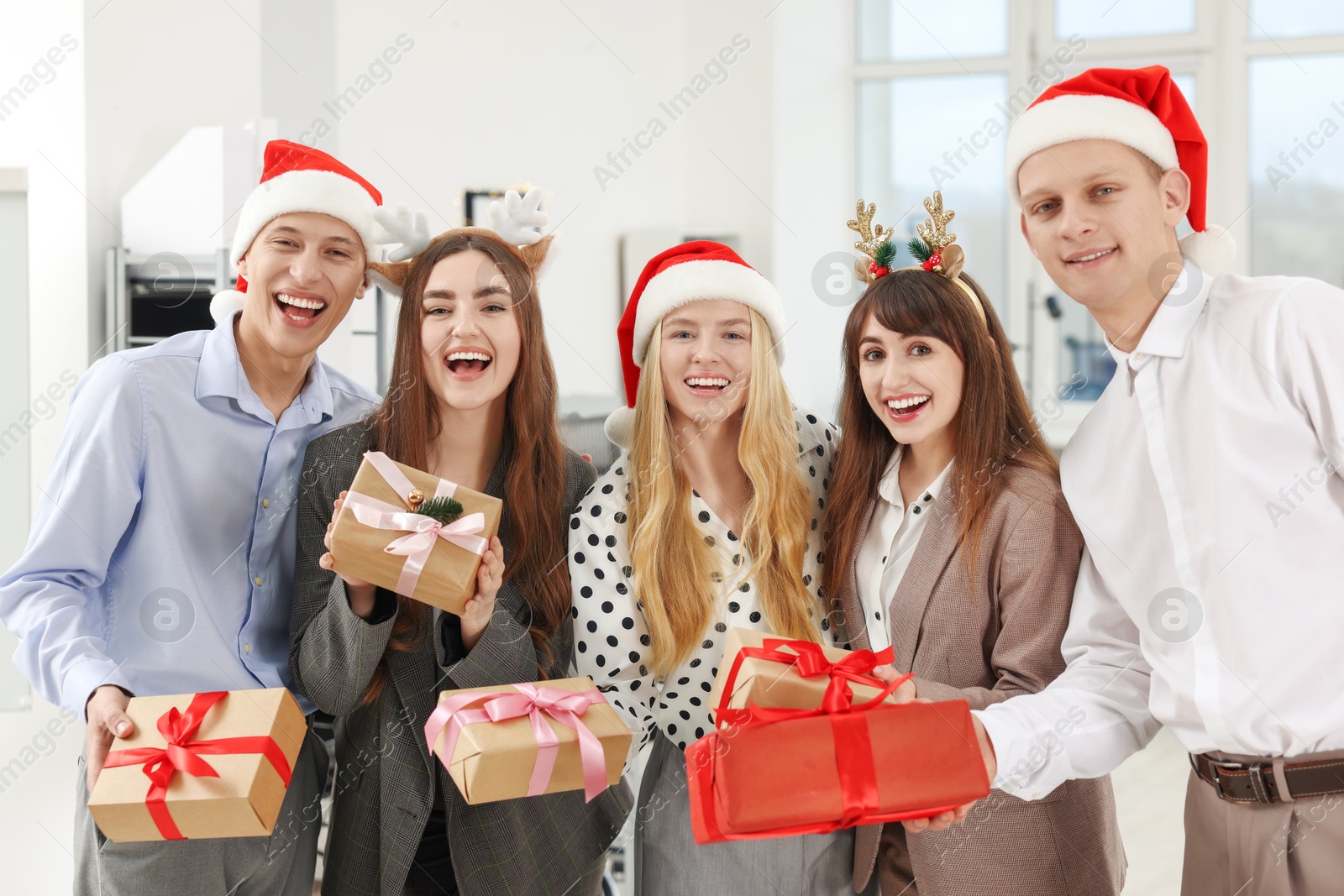 Photo of Happy coworkers with gifts at office Christmas party