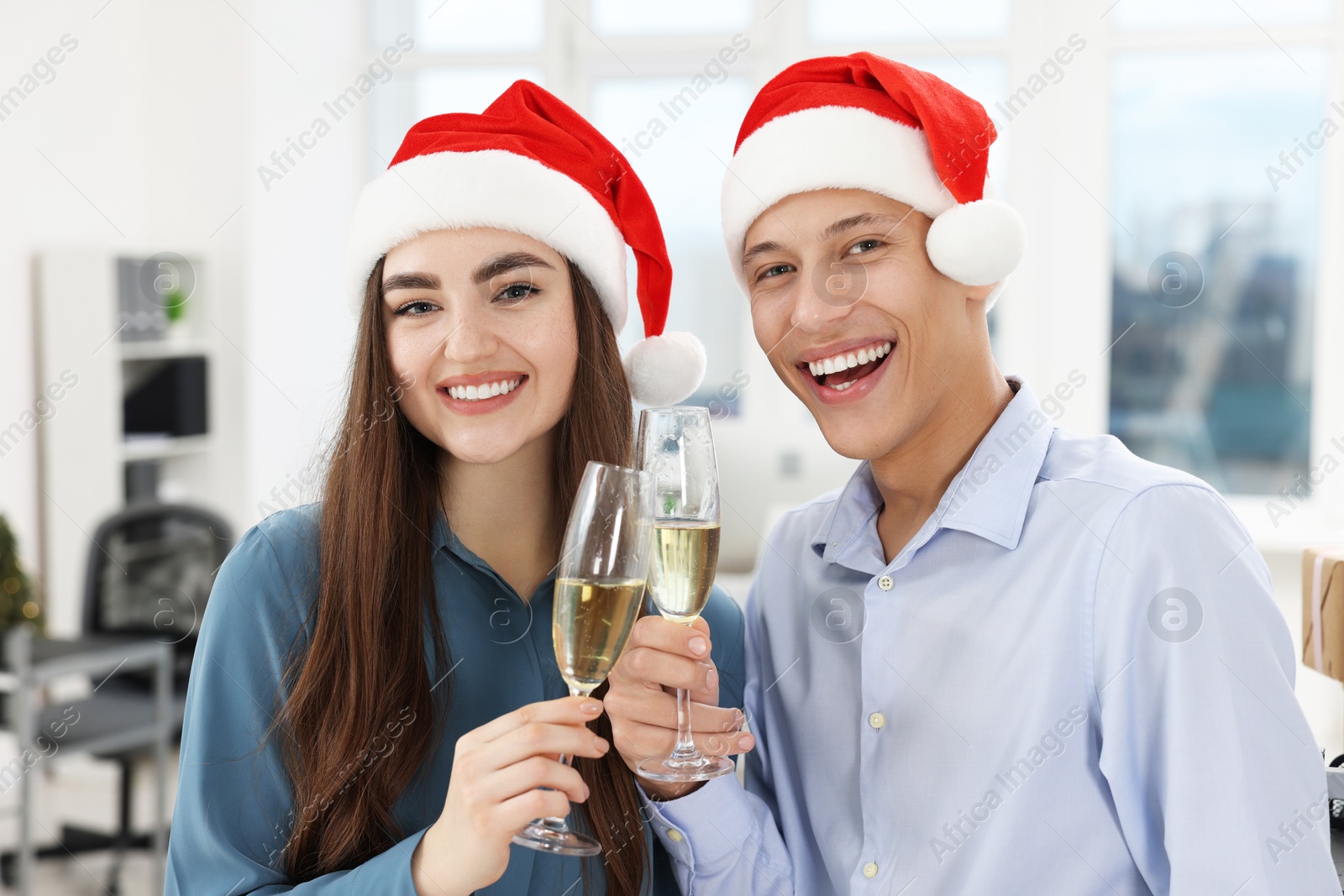 Photo of Happy coworkers clinking glasses of wine during office Christmas party