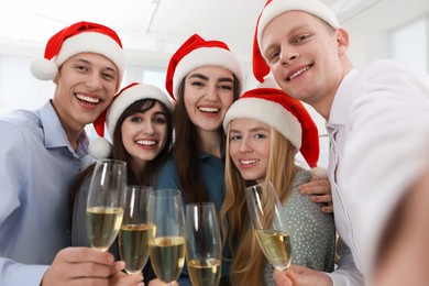 Photo of Smiling colleagues taking selfie at Christmas party in office