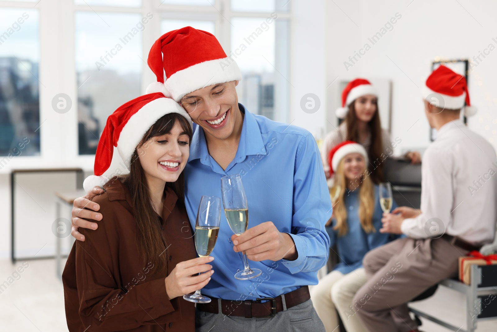 Photo of Happy coworkers clinking glasses of wine during office Christmas party