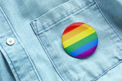 Image of White button badge in LGBT colors pinned on denim shirt, top view. Tolerance and acceptance