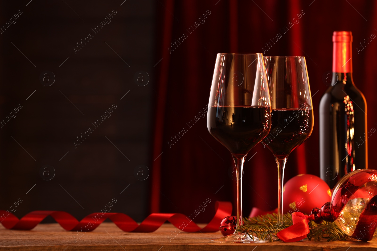 Photo of Red wine and Christmas decor on wooden table. Space for text