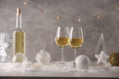 Photo of White wine, Christmas decor and artificial snow on light grey background