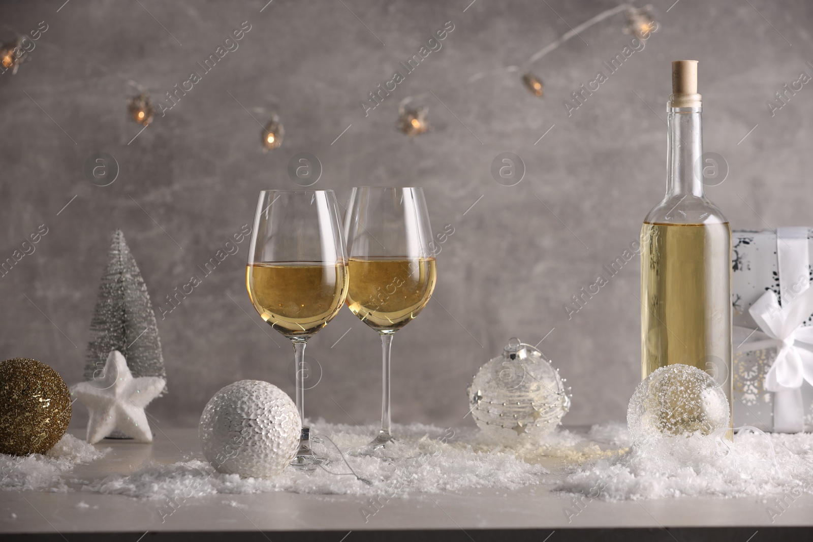 Photo of White wine, Christmas decor and artificial snow on light grey background