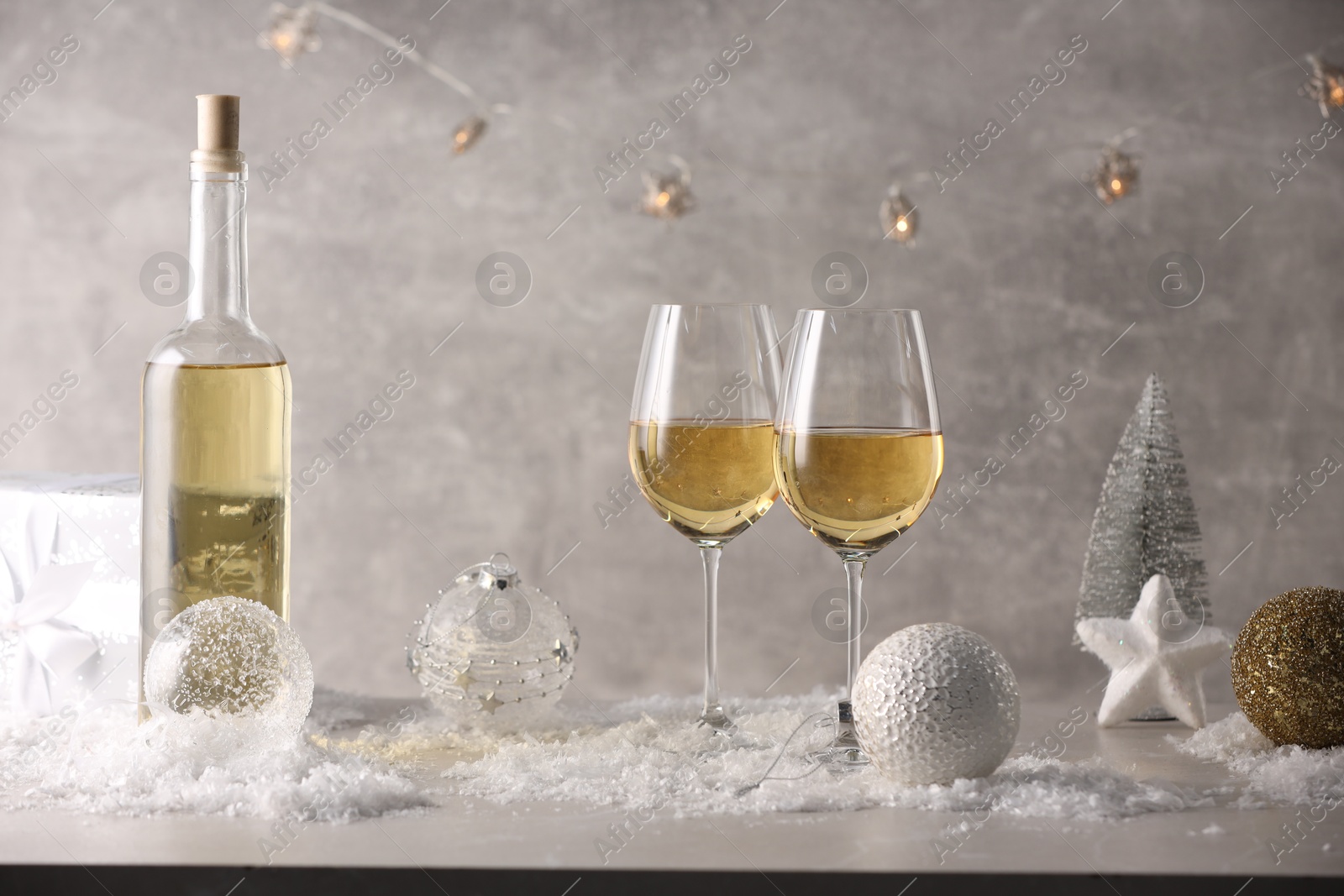 Photo of White wine, Christmas decor and artificial snow on light grey background