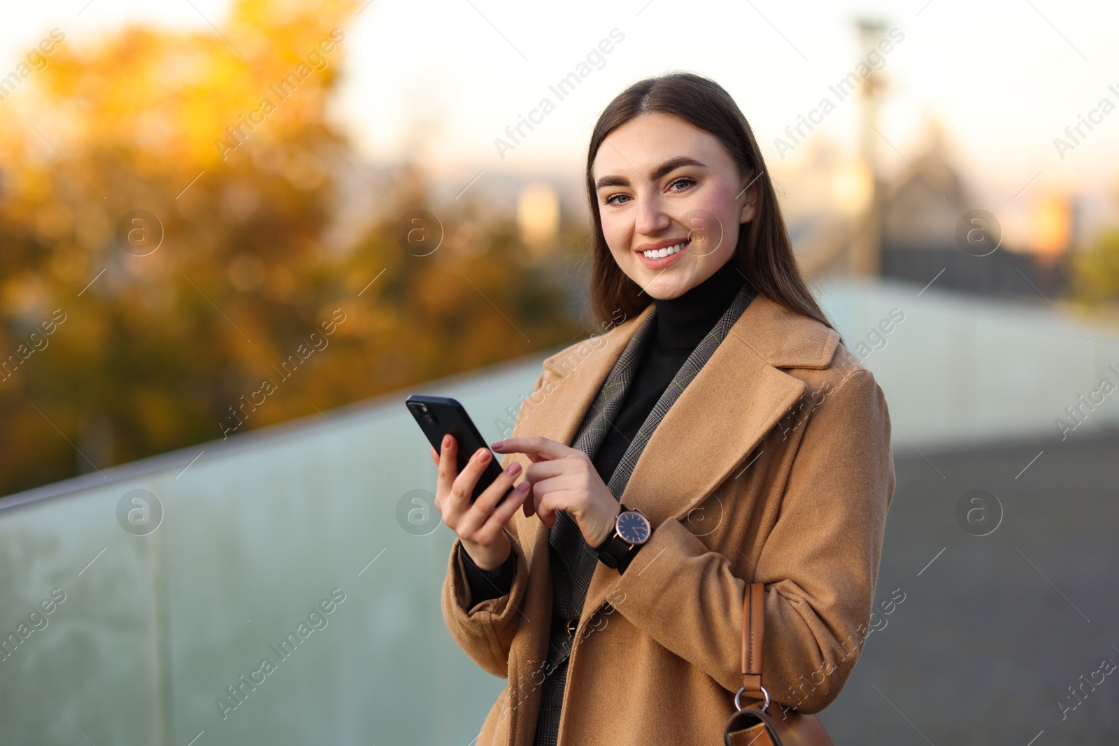 Photo of Smiling businesswoman in stylish suit with smartphone outdoors. Space for text