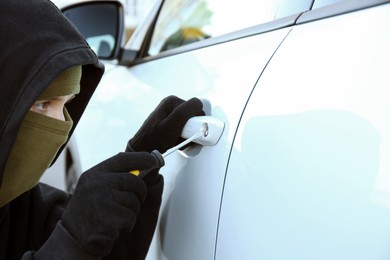 Photo of Thief with screwdriver breaking into car, closeup