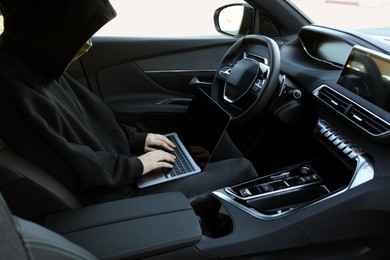 Photo of Thief hacking car system with laptop inside vehicle, closeup