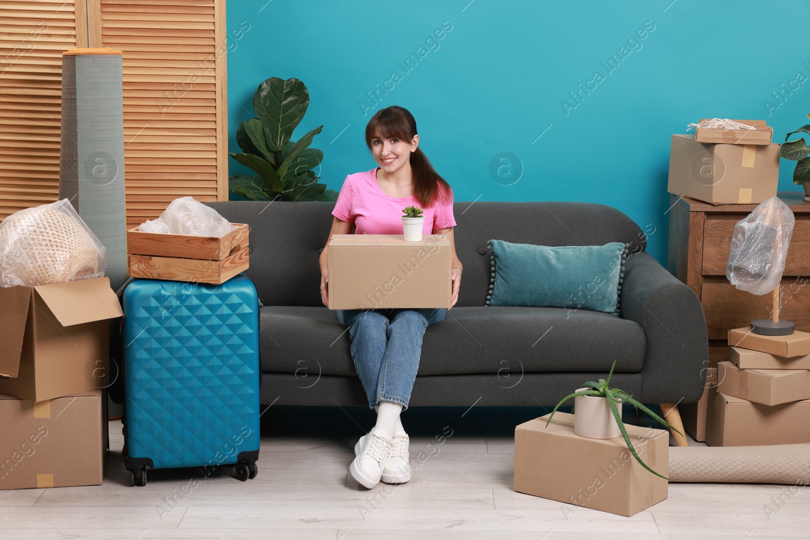 Photo of Happy woman with different stuff in new apartment. Housewarming party