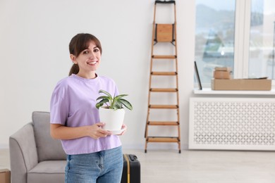 Photo of Happy woman with houseplant in new apartment. Housewarming party