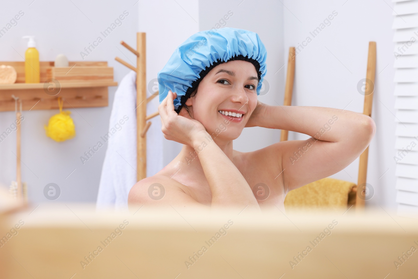 Photo of Woman wearing blue shower cap in bathroom