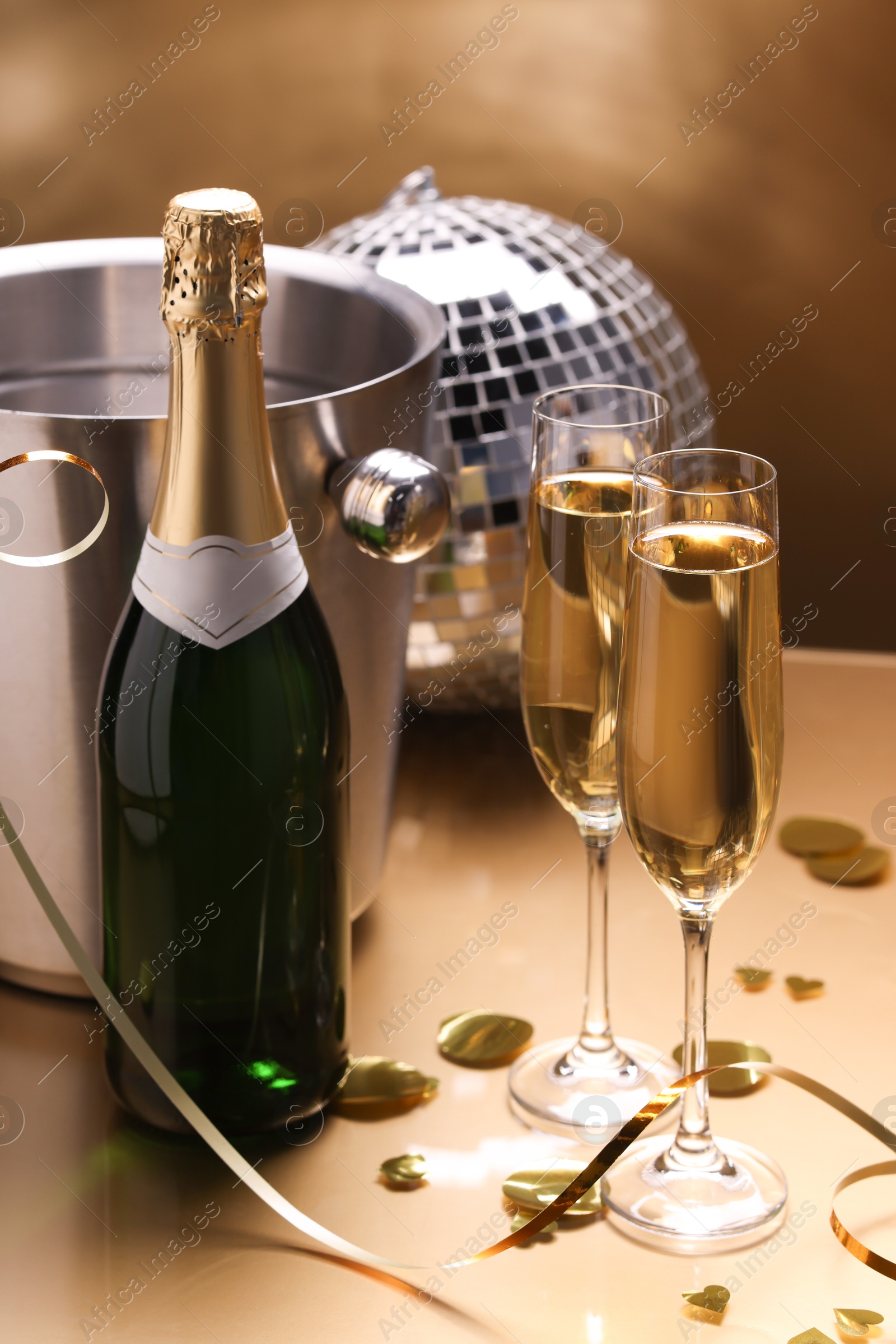 Photo of Champagne in glasses and ice bucket with bottle on golden background