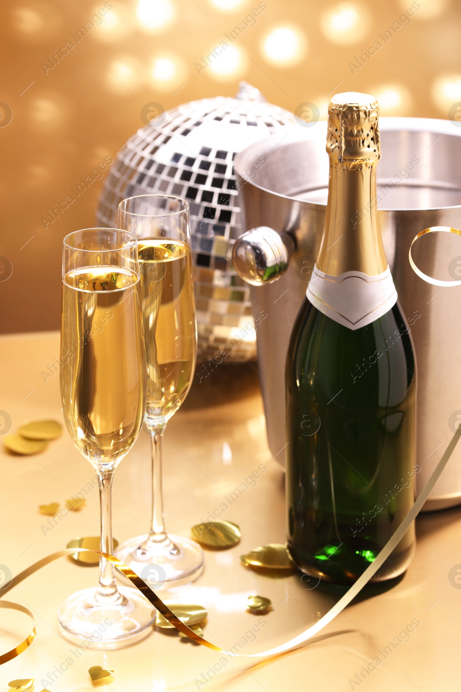 Photo of Champagne in glasses and ice bucket with bottle on golden background