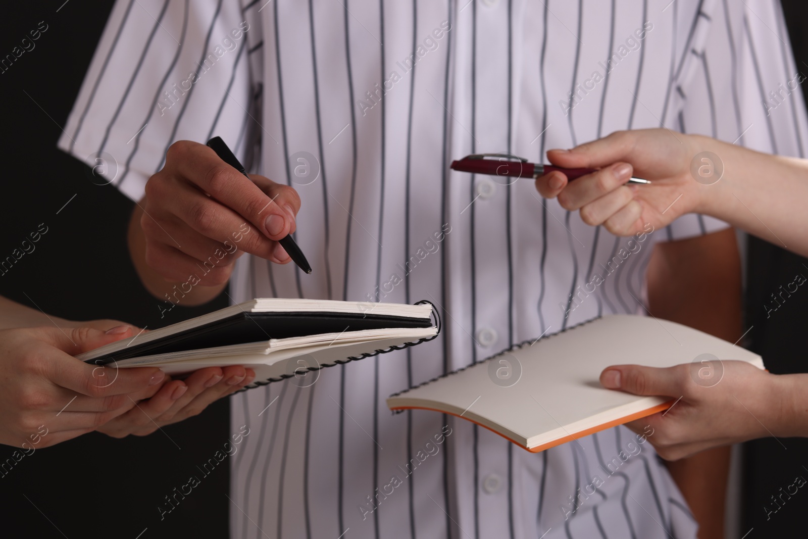 Photo of Baseball player signing autograph in notebook against black background, closeup