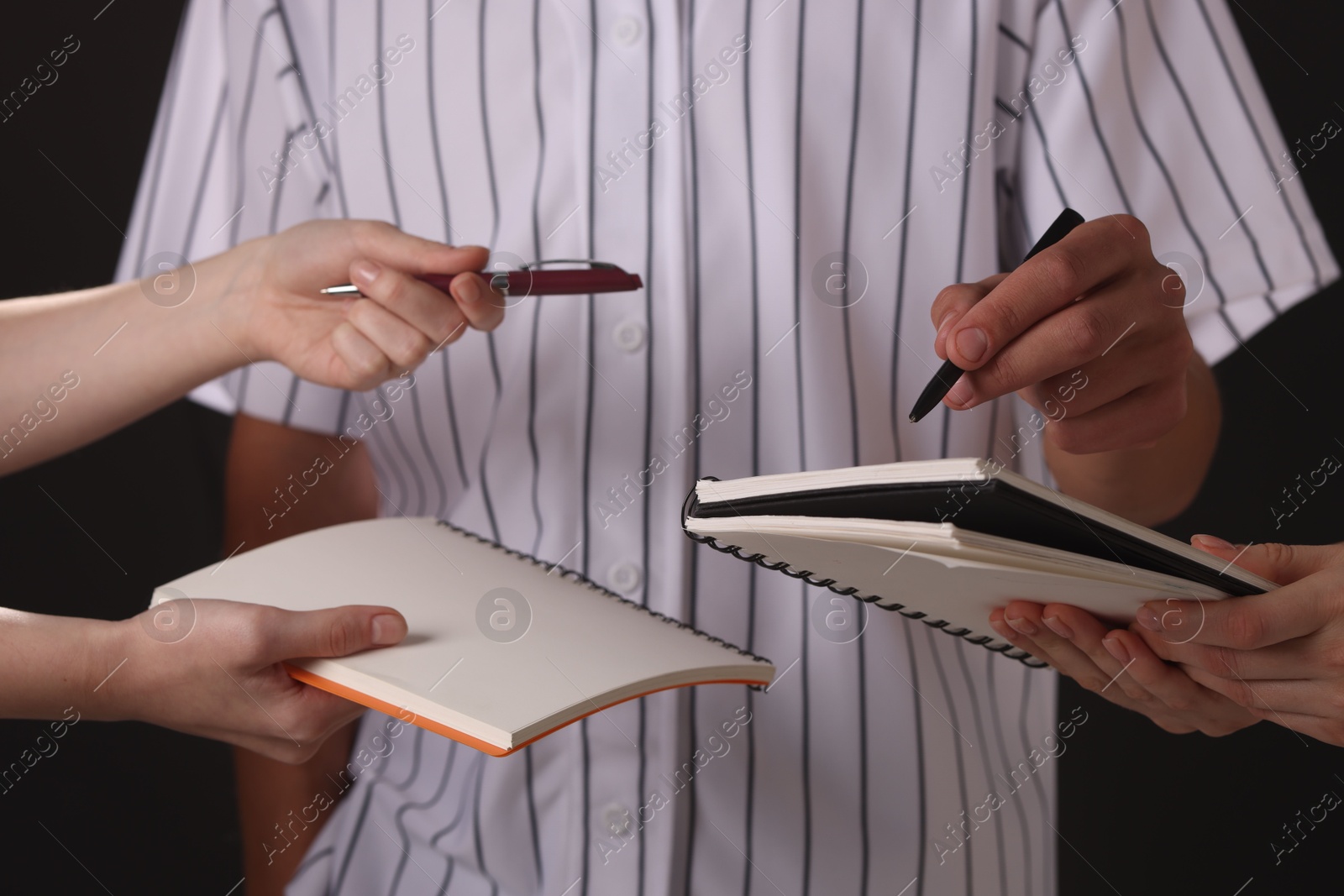 Photo of Baseball player signing autograph in notebook against black background, closeup