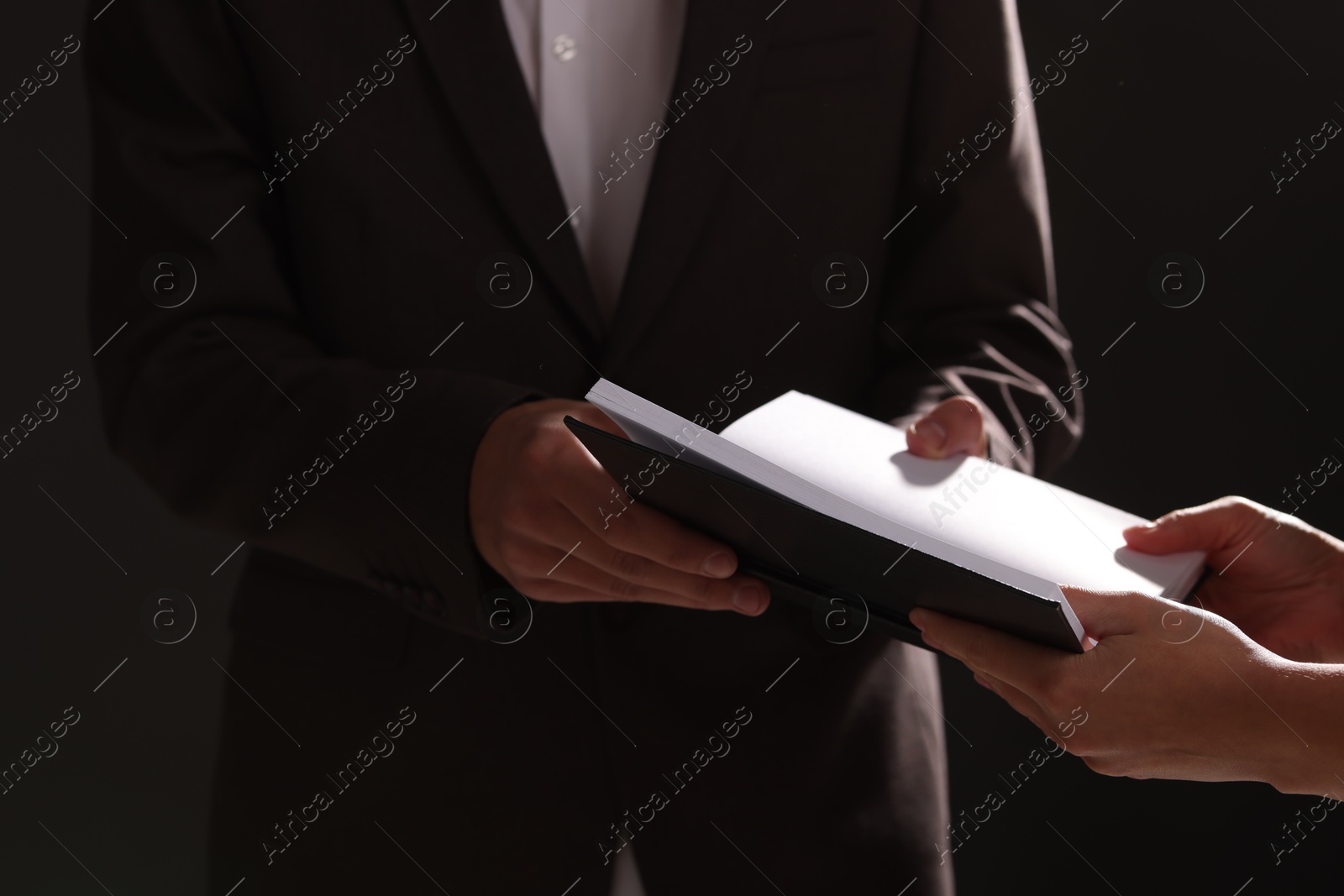 Photo of Writer signing autograph in book on black background, closeup