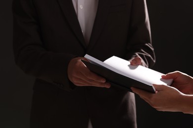 Writer signing autograph in book on black background, closeup