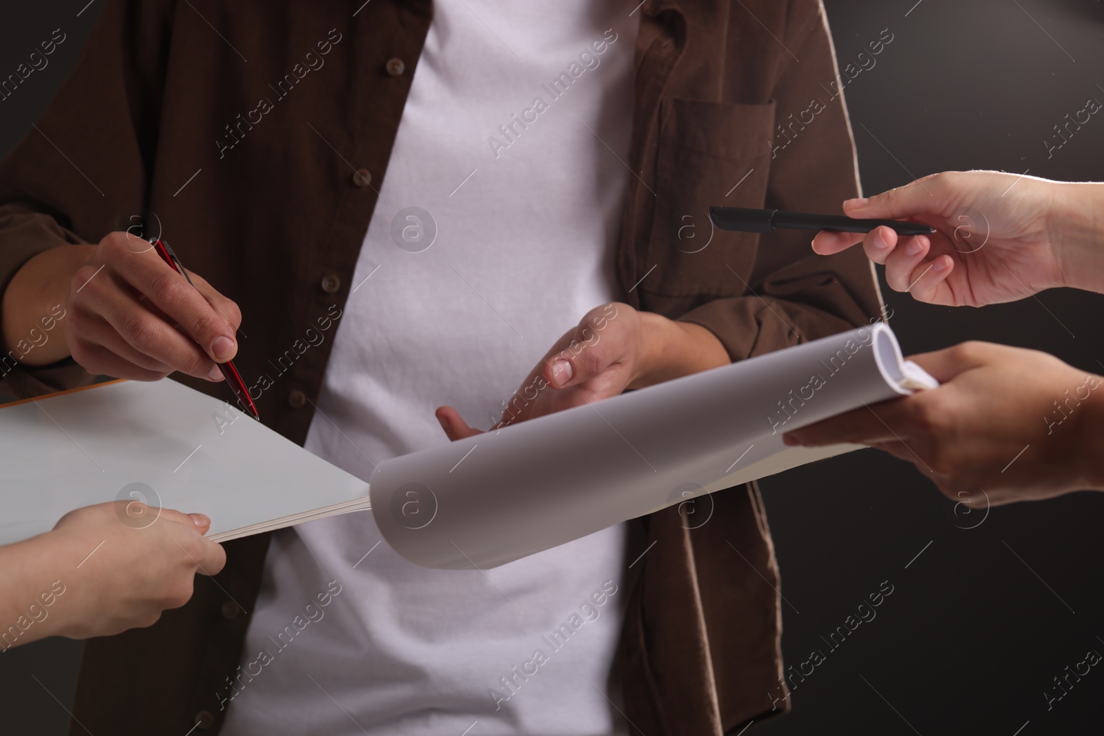 Photo of Man signing autograph in notebook on black background, closeup