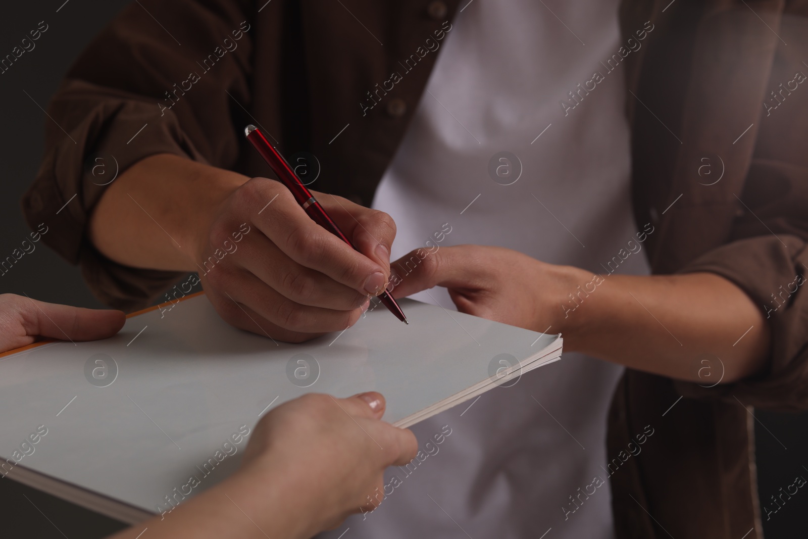 Photo of Man signing autograph in notebook, closeup view