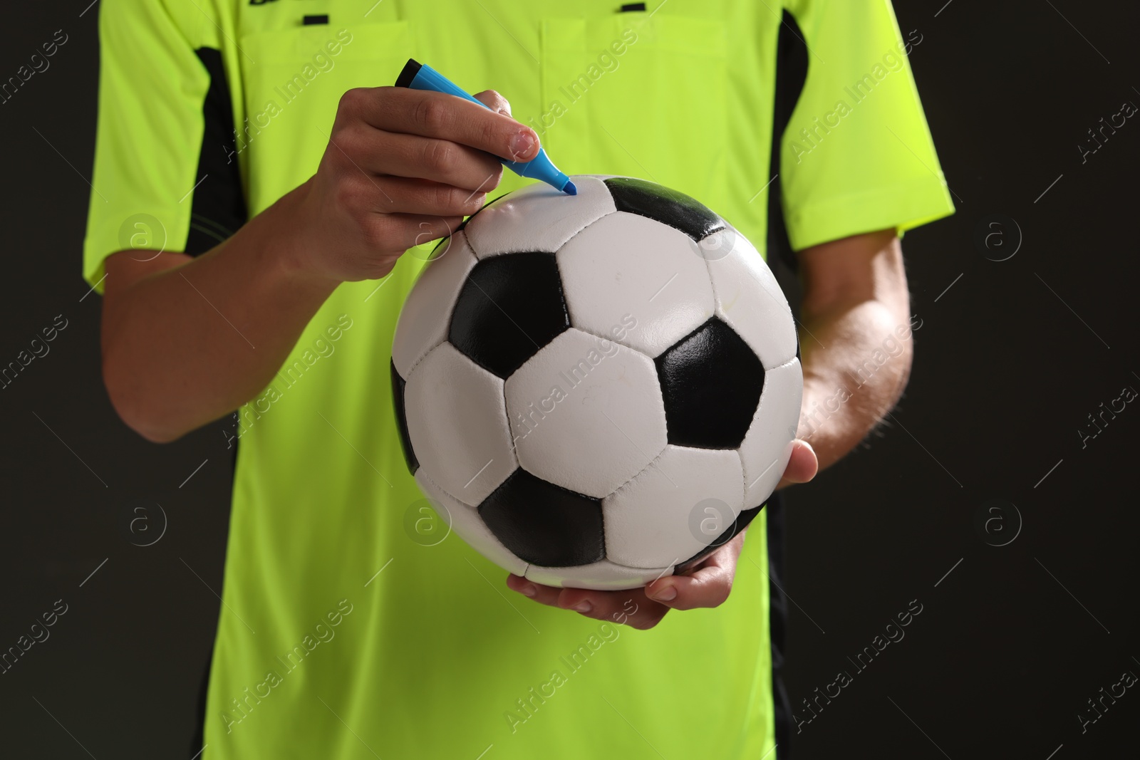 Photo of Professional player signing autograph on ball against black background, closeup