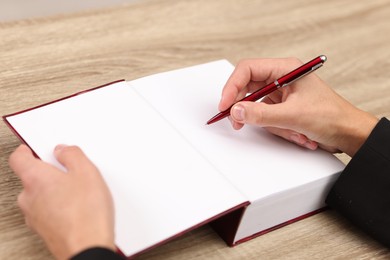 Writer signing autograph in book at wooden table indoors, closeup