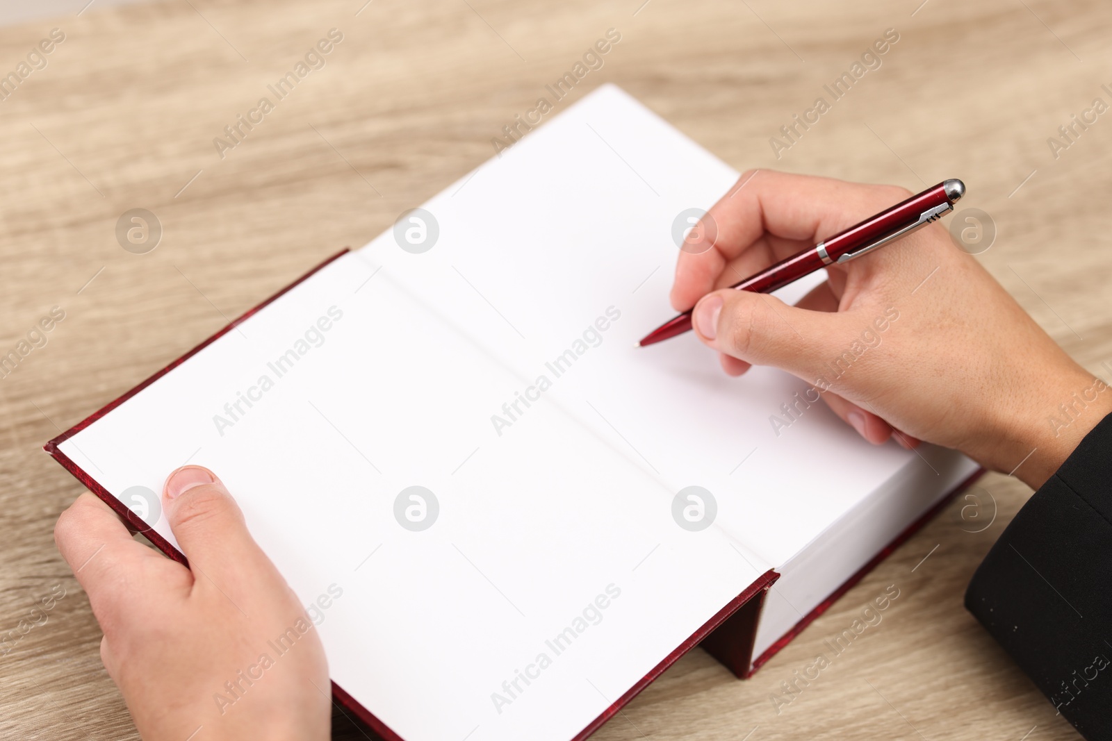 Photo of Writer signing autograph in book at wooden table indoors, closeup