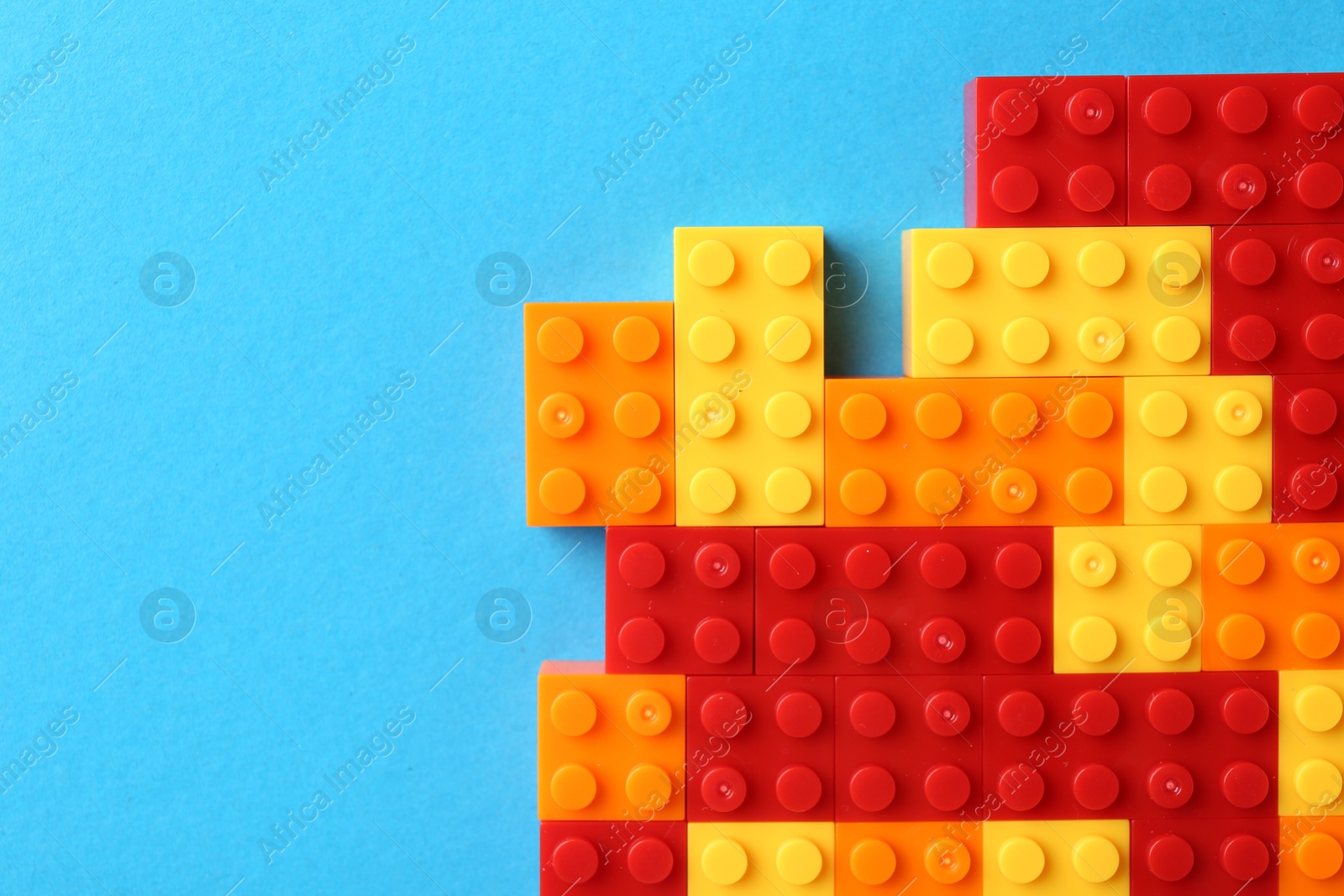 Photo of Constructor toy. Many colorful building blocks on light blue background, top view. Space for text