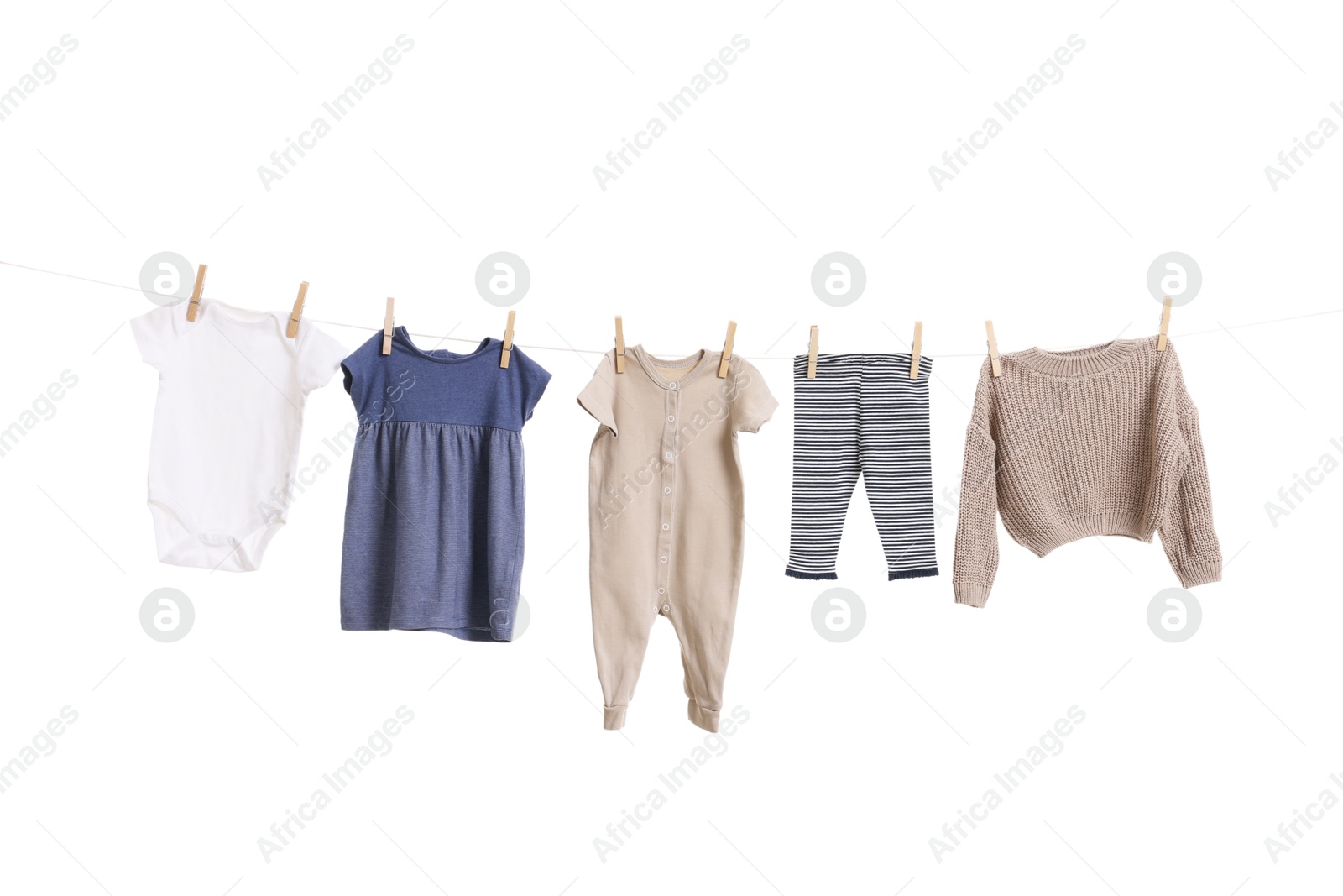 Photo of Different baby clothes drying on laundry line against white background