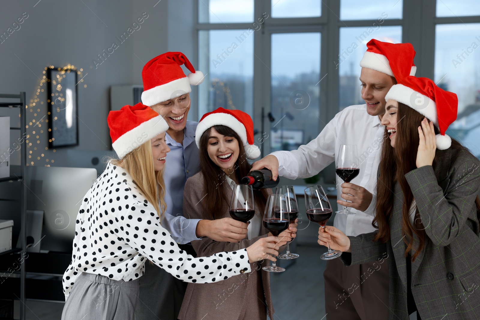 Photo of Man pouring wine for his colleagues at office Christmas party