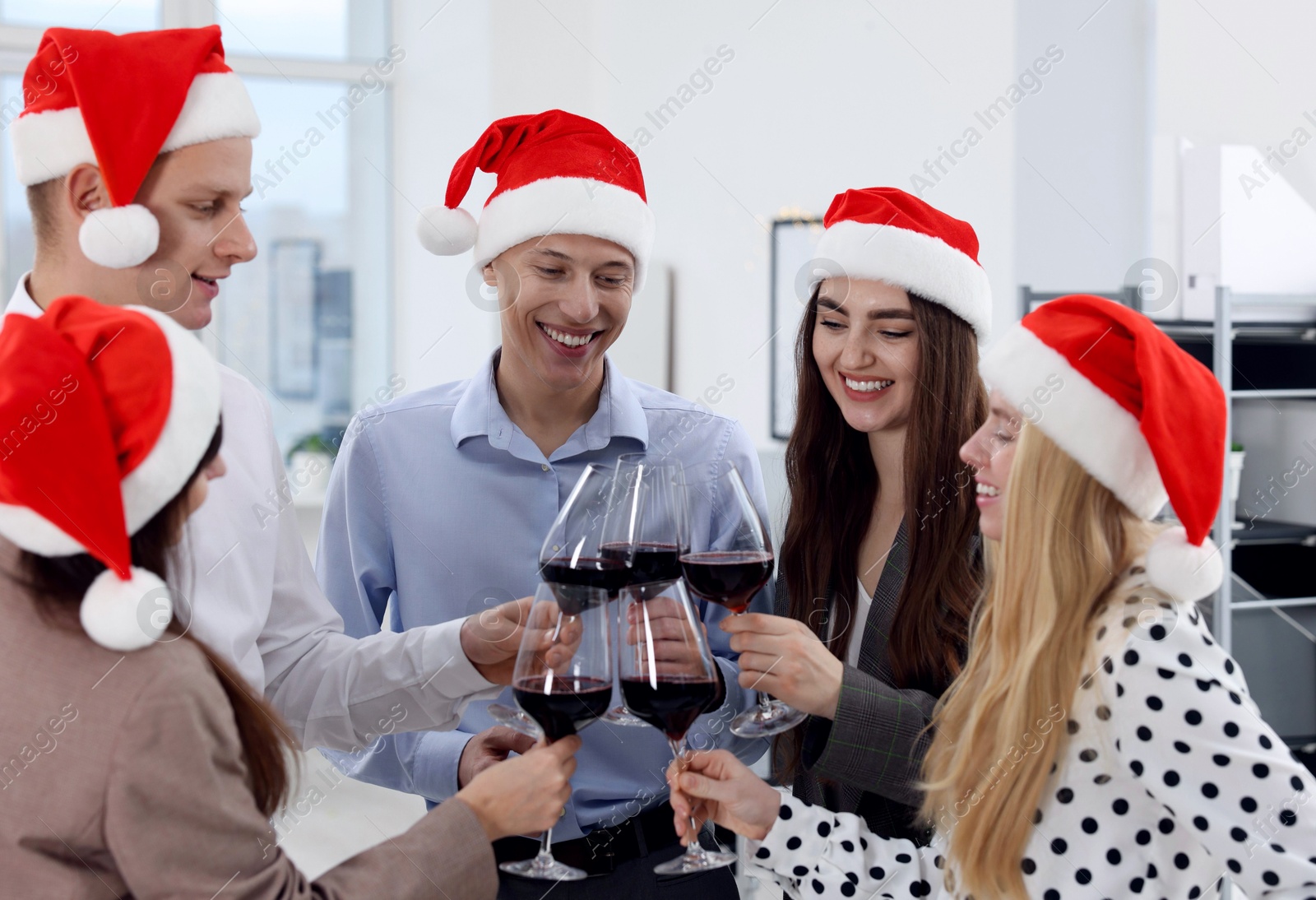 Photo of Happy coworkers clinking glasses of wine during office Christmas party