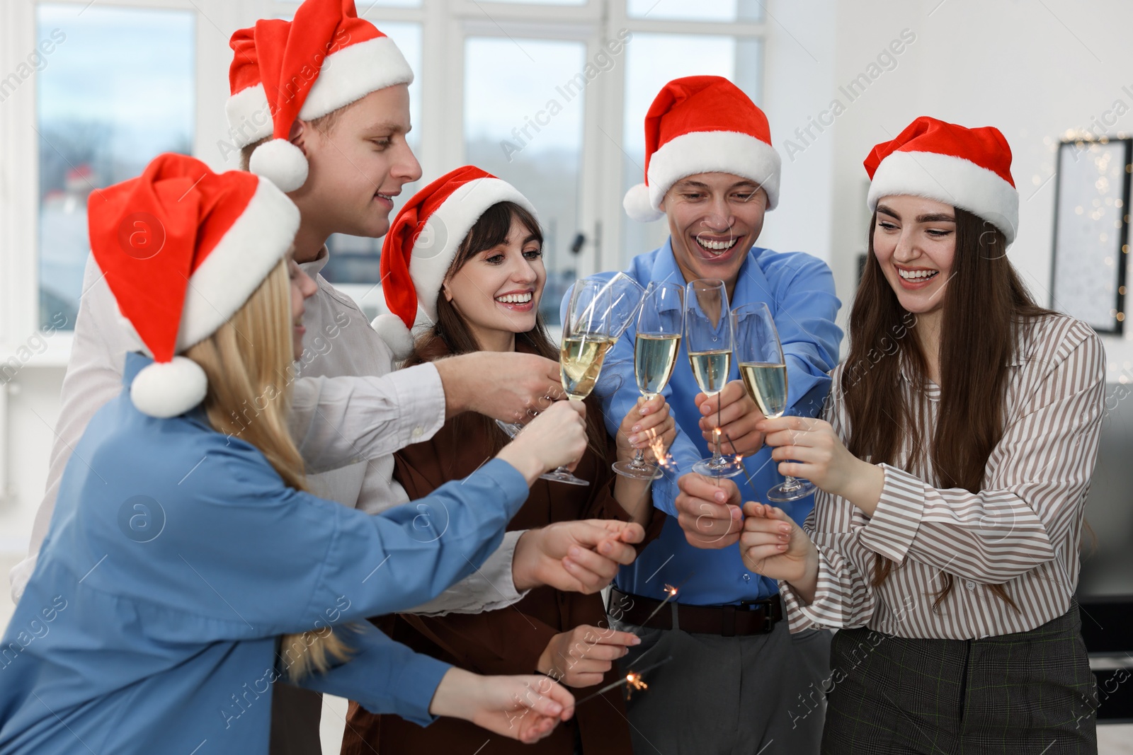 Photo of Happy coworkers clinking glasses of wine during office Christmas party