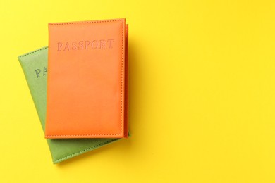 Photo of Passports in color covers on yellow background, top view. Space for text