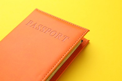 Photo of Passport in orange cover on yellow background, closeup