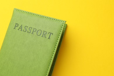 Photo of Passport in green cover on yellow background, top view. Space for text