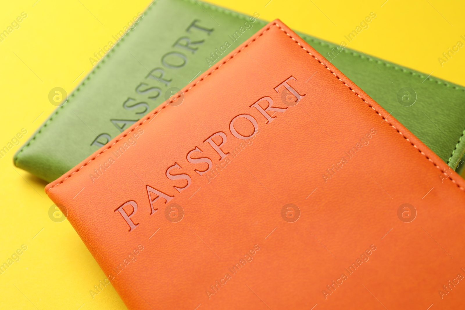 Photo of Passports in color covers on yellow background, closeup