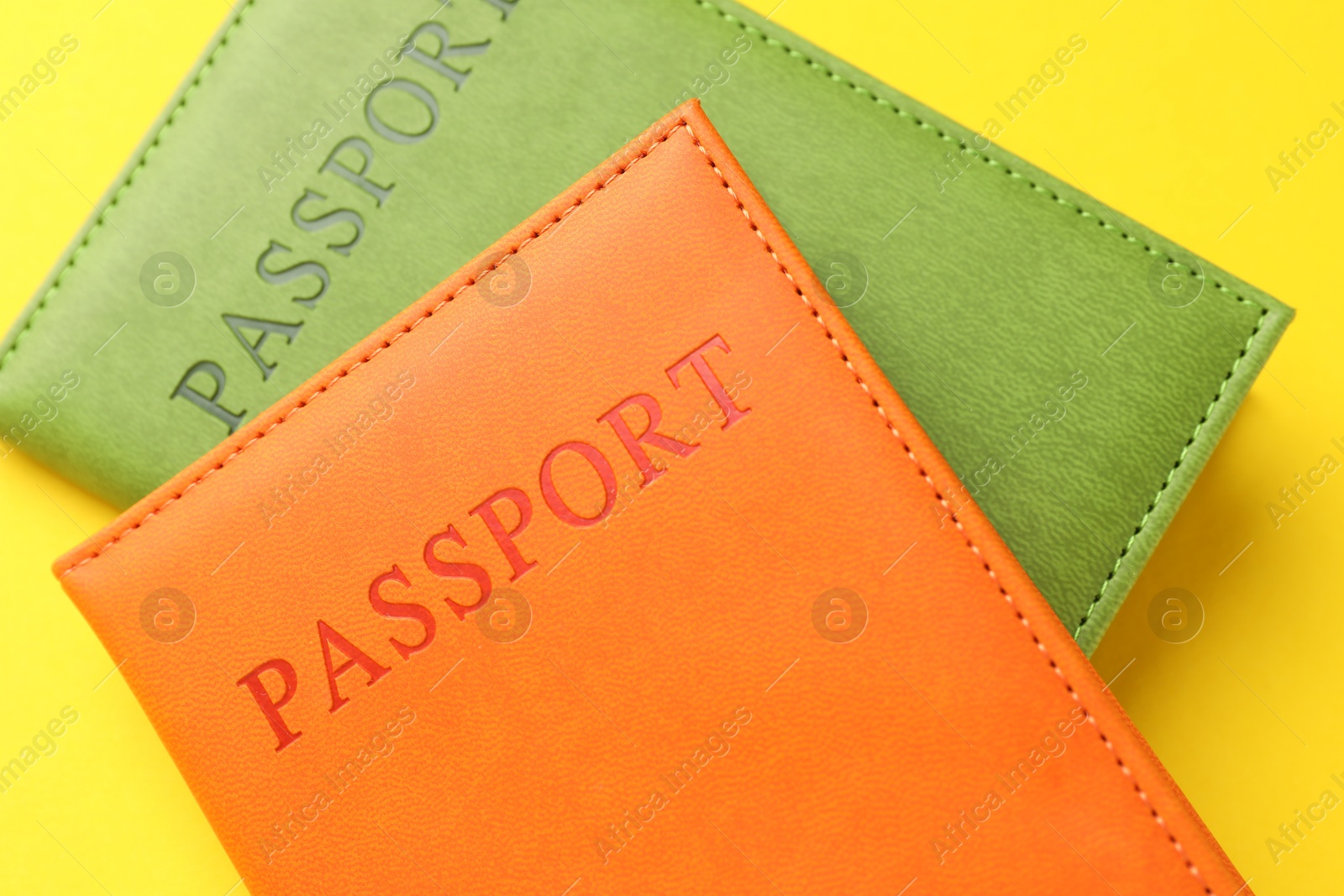 Photo of Passports in color covers on yellow background, closeup