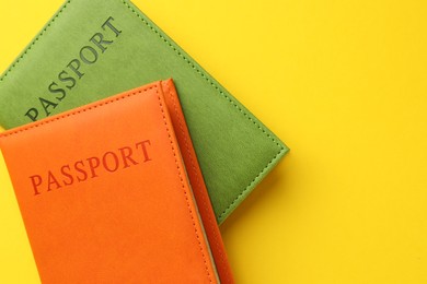 Photo of Passports in color covers on yellow background, top view. Space for text