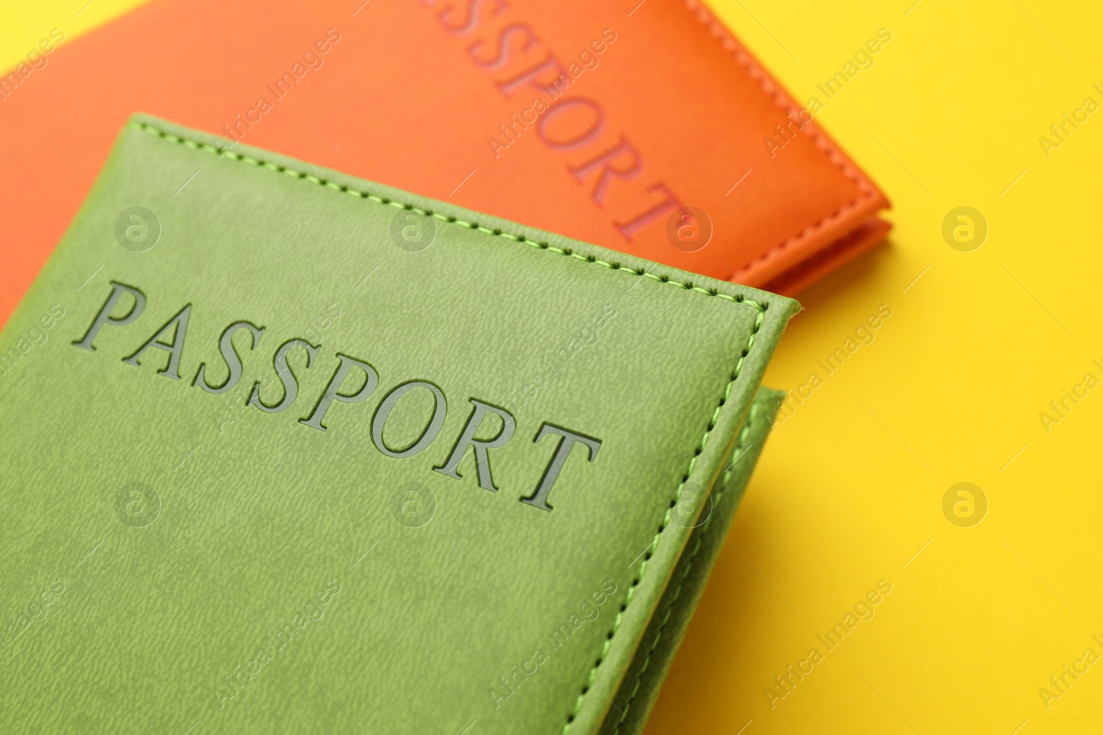 Photo of Passports in color covers on yellow background, closeup