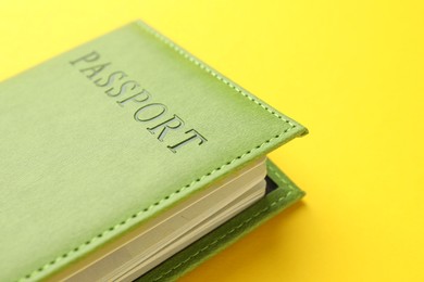 Photo of Passport in green cover on yellow background, closeup