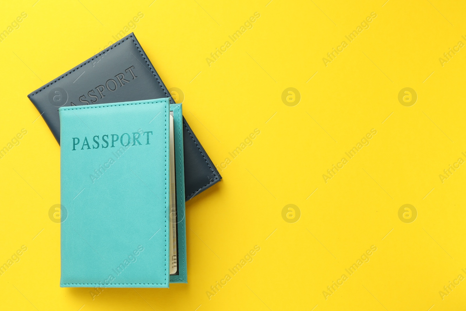 Photo of Passports in color covers on yellow background, top view. Space for text