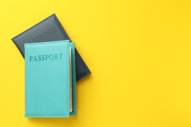 Photo of Passports in color covers on yellow background, top view. Space for text