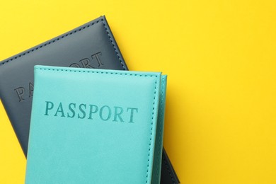 Photo of Passports in color covers on yellow background, top view. Space for text