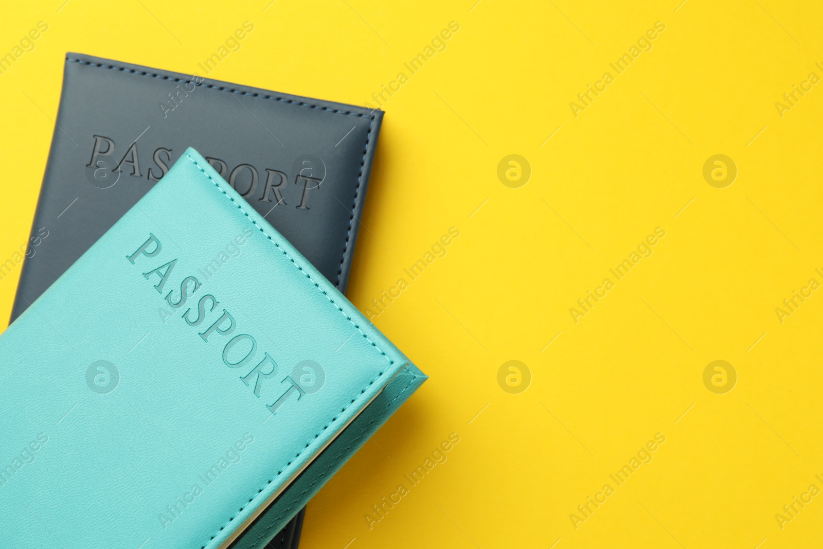 Photo of Passports in color covers on yellow background, top view. Space for text