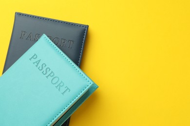 Photo of Passports in color covers on yellow background, top view. Space for text