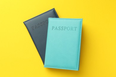 Photo of Passports in color covers on yellow background, top view