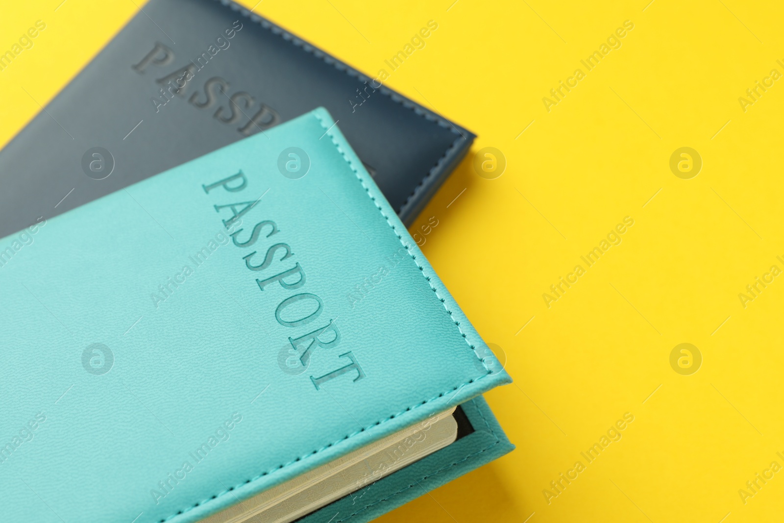 Photo of Passports in color covers on yellow background, closeup. Space for text