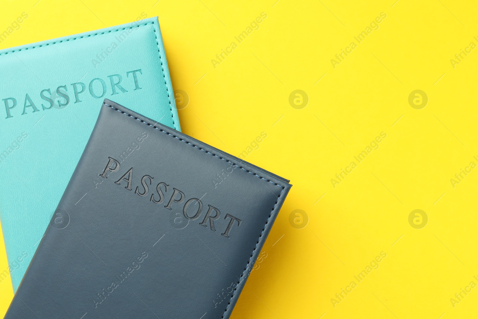 Photo of Passports in color covers on yellow background, top view. Space for text