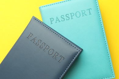 Photo of Passports in color covers on yellow background, top view