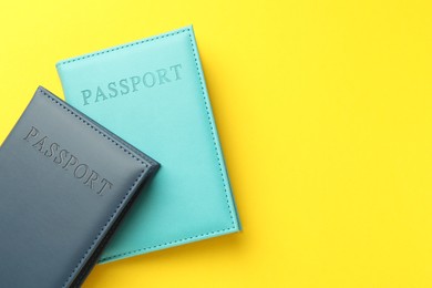 Photo of Passports in color covers on yellow background, top view. Space for text